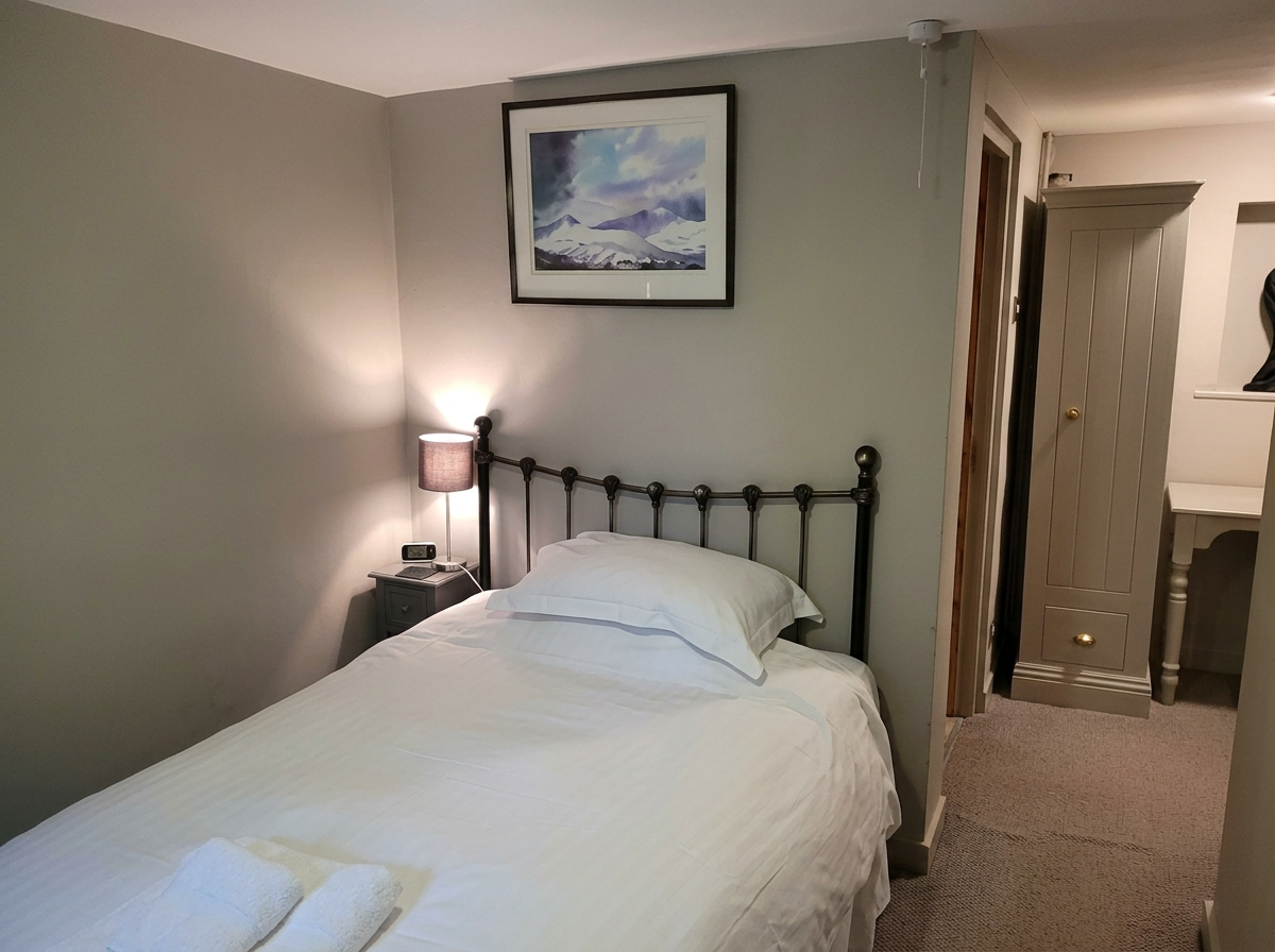 Cosy single bedroom with brass bedstead and framed mountain print
